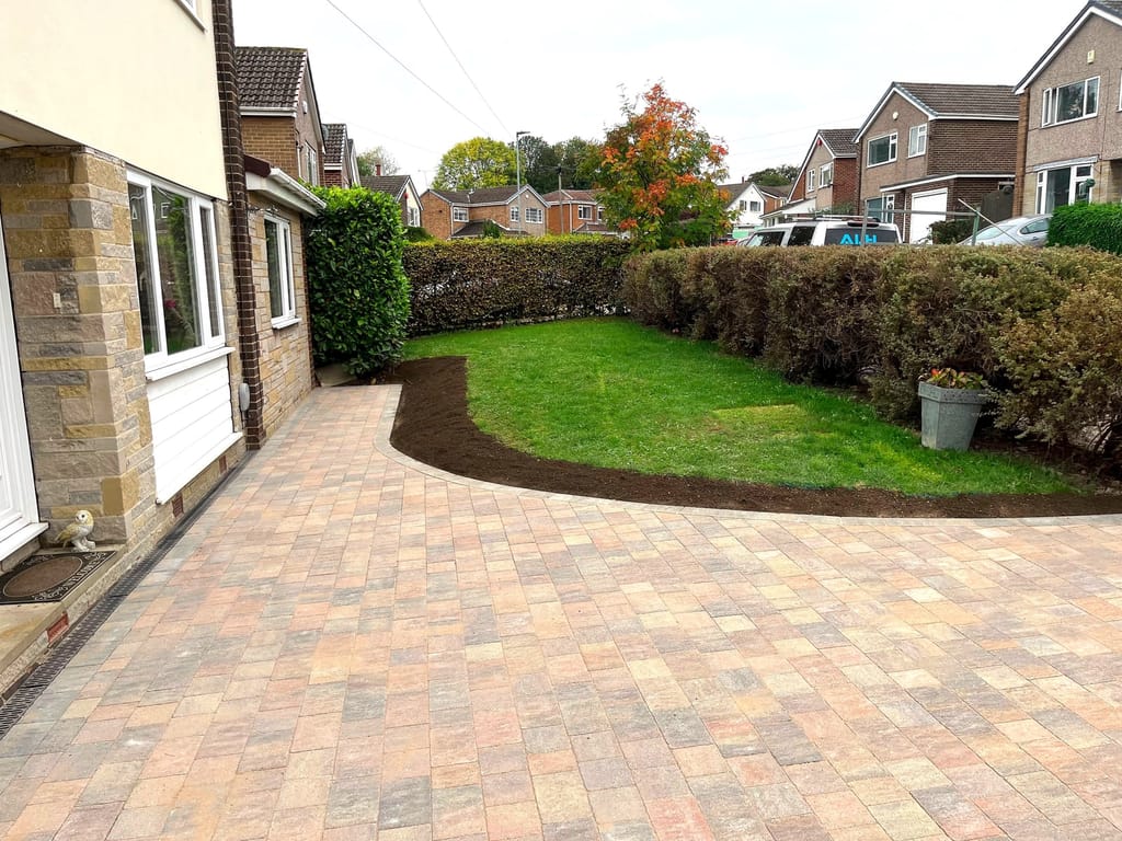 Block paved driveway and turning area beside a curved lawn in Castleford