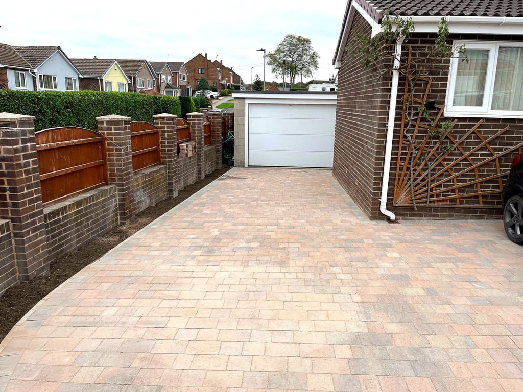 Block paved driveway between brick piers leading to a white garage door