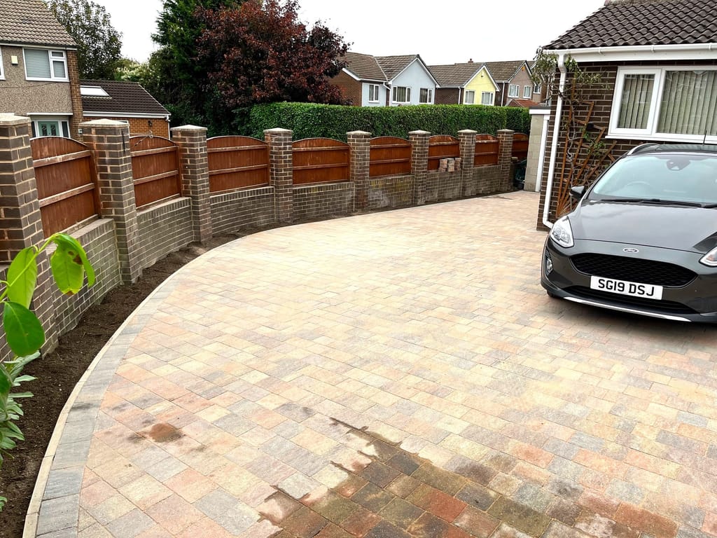 Curved block paved driveway with a new brick pier and timber panel boundary wall