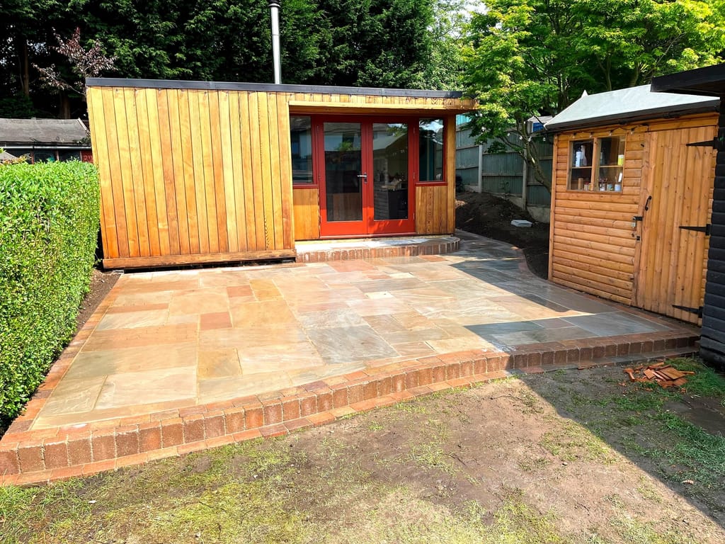 Sandstone terrace with a brick edge laid in front of a cedar clad garden room