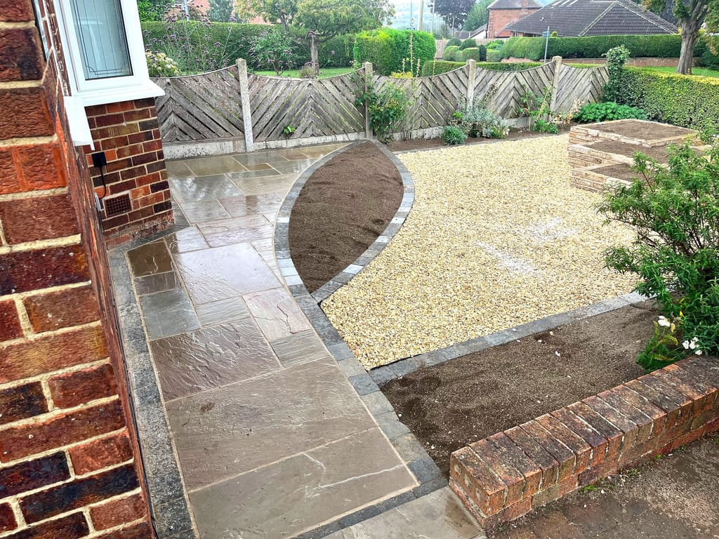 Sandstone path curving round a gravel bed with raised brick planters