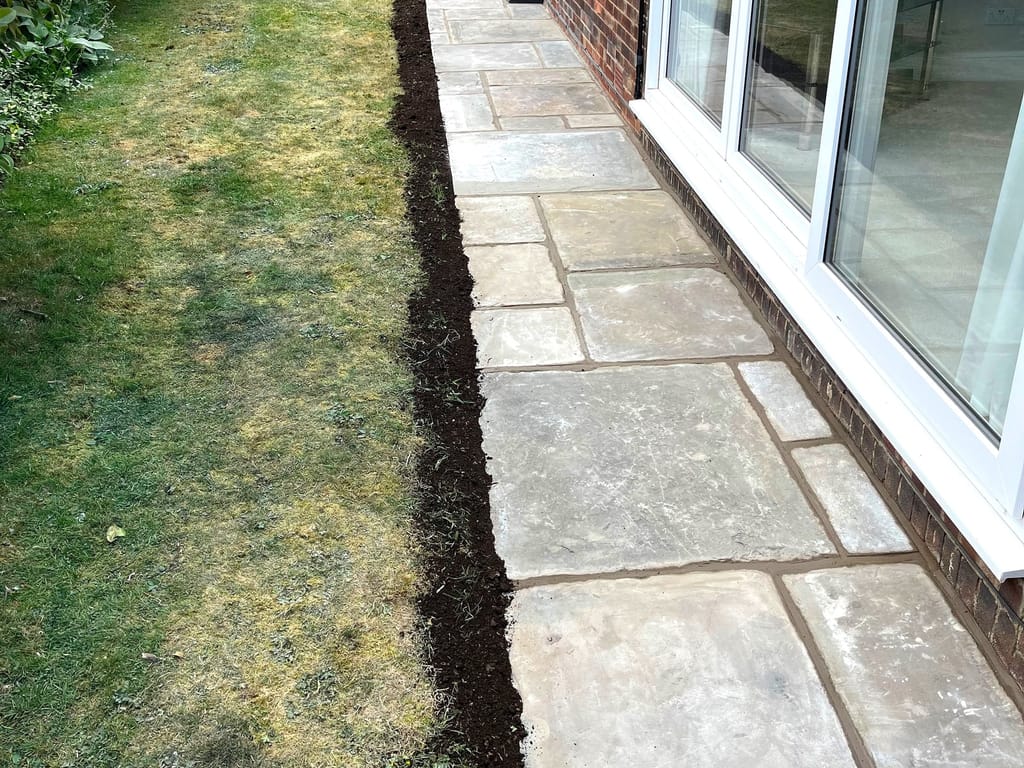 Sandstone path running the length of a house beside a freshly cut lawn