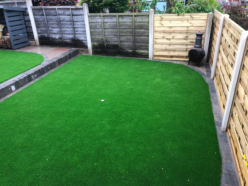 Rectangular artificial lawn with charcoal block edging and a raised brick border
