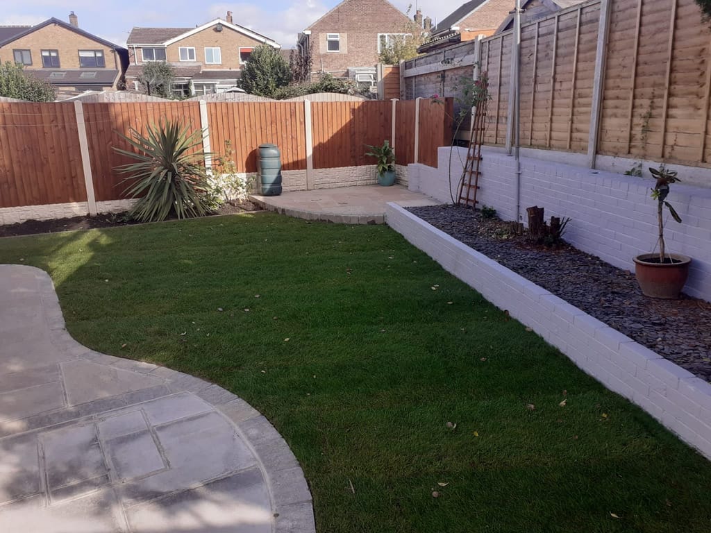 Lawn beside a curved slab path and a white painted brick retaining wall