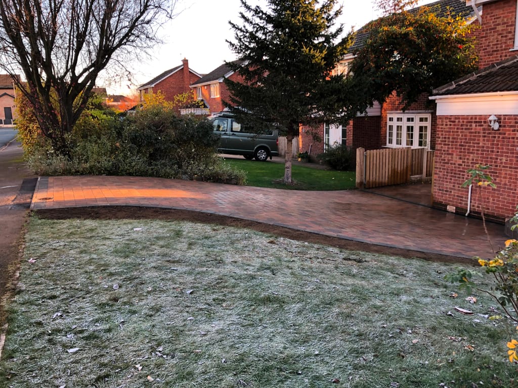 Block paved driveway sweeping past a frosted lawn to a red brick detached house