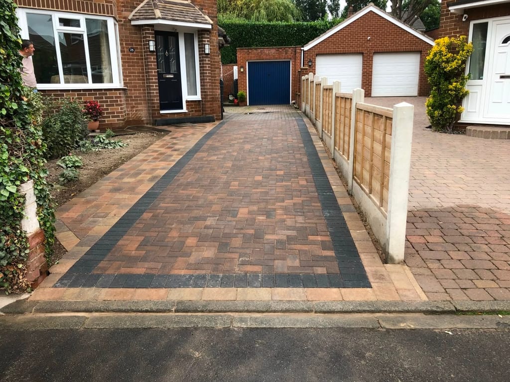 Block paved driveway with a charcoal border running past a bungalow towards a double garage
