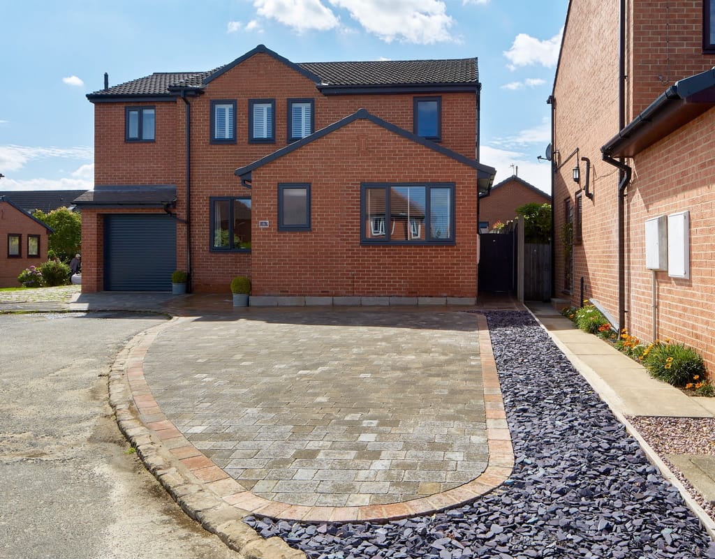 Curved block driveway with a contrasting border beside a bed of slate chippings