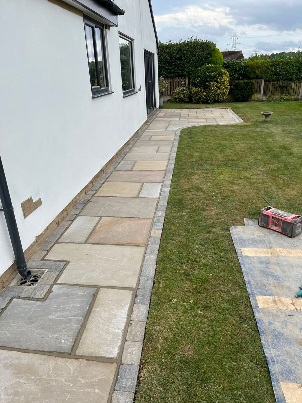 Sandstone path with grey sett edging running the length of a white rendered bungalow