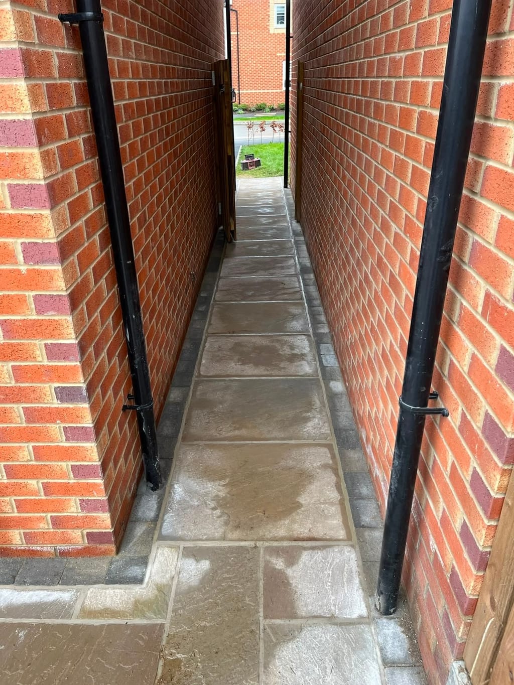Narrow sandstone passage with sett borders between the brick flanks of two houses