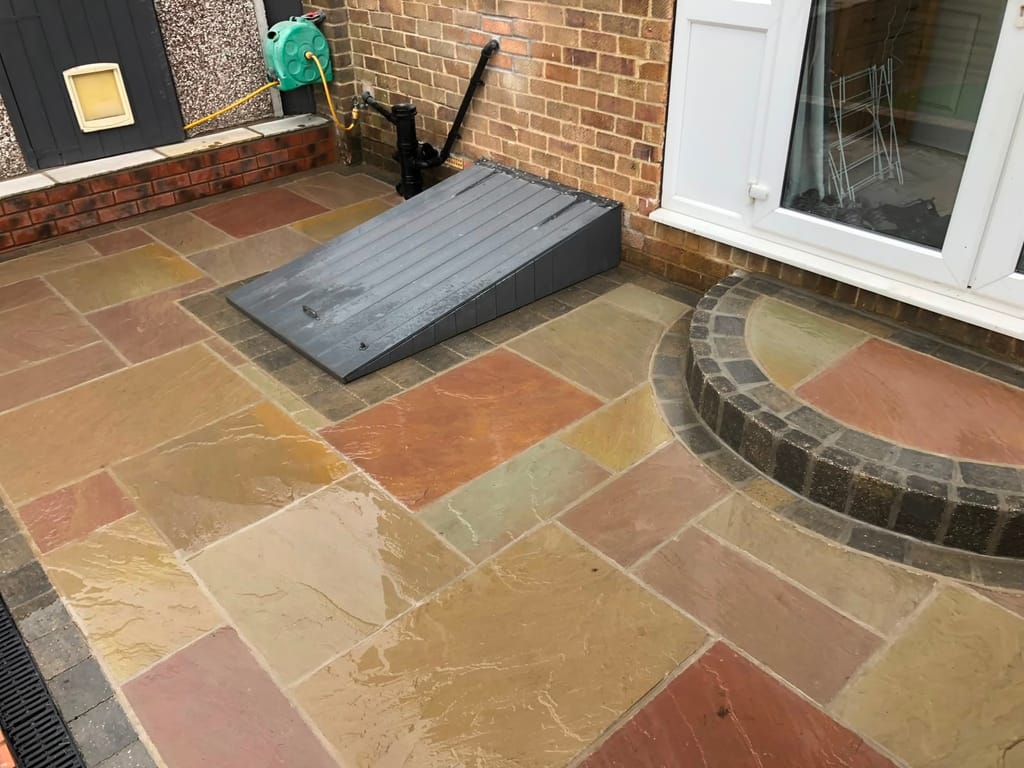 Sandstone patio with a curved sett step at white french doors and a coal bunker cover
