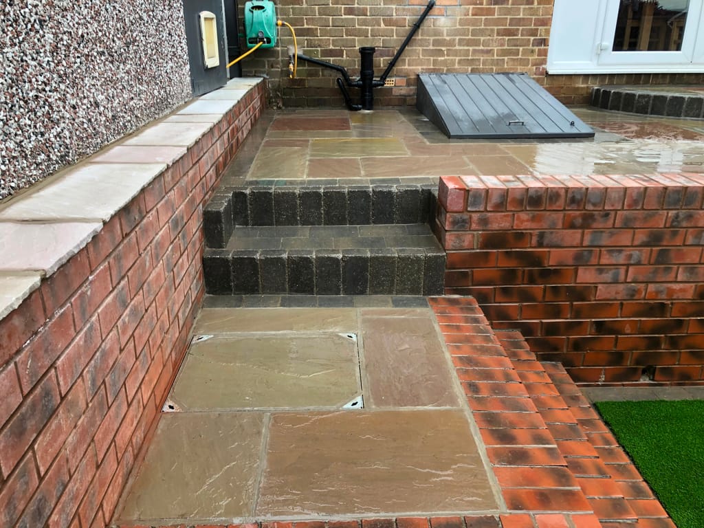 Sandstone terrace stepping down between red brick retaining walls on charcoal block treads