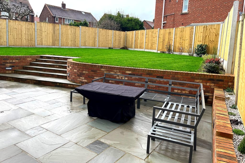 Sandstone terrace with a bench and firepit below a brick retained lawn